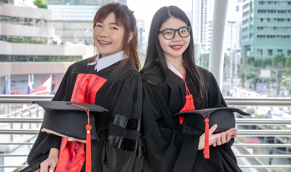 Two university students wear gowns after graduation