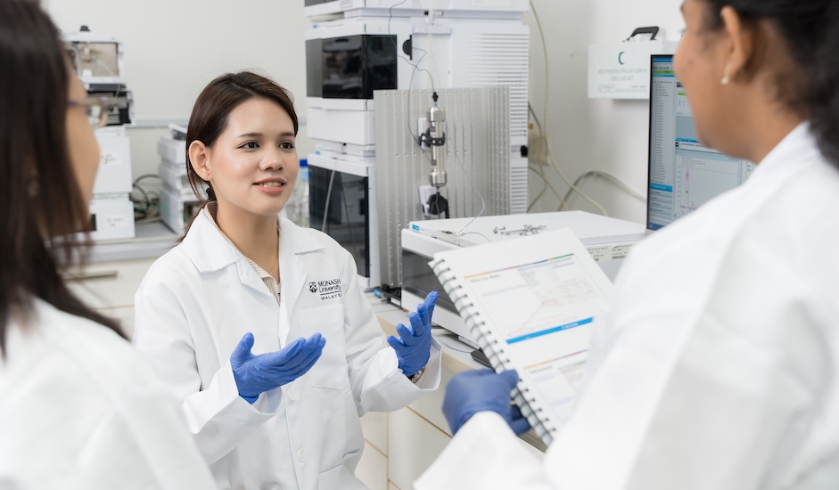 Pharmacy students discussing research data in a laboratory at Monash Malaysia
