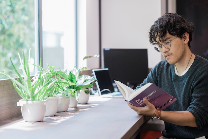 A full-time student reading a book in a study space at Monash Malaysia