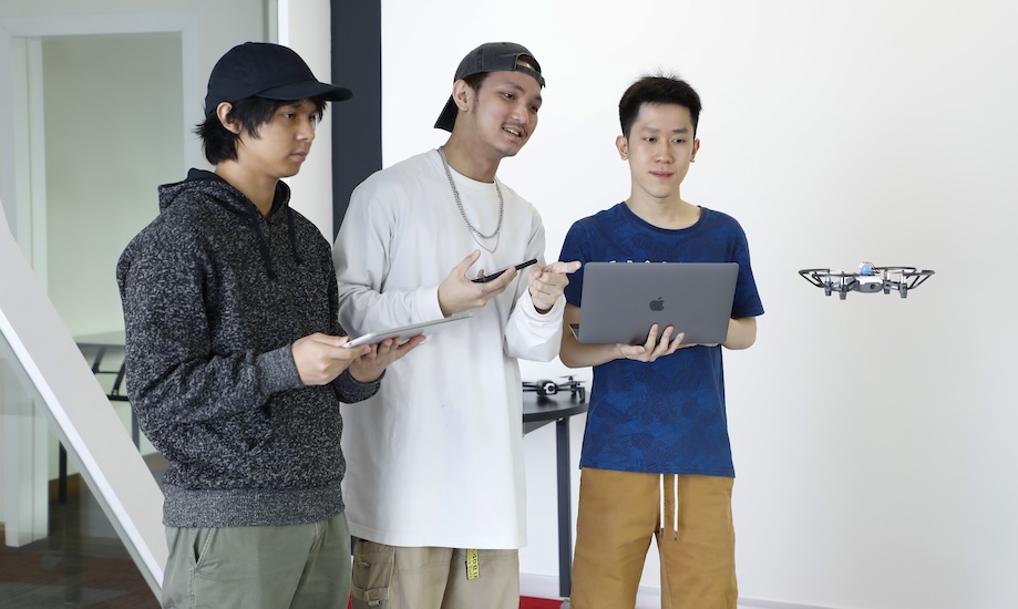 Computer science students operating a drone with a laptop at Monash Malaysia