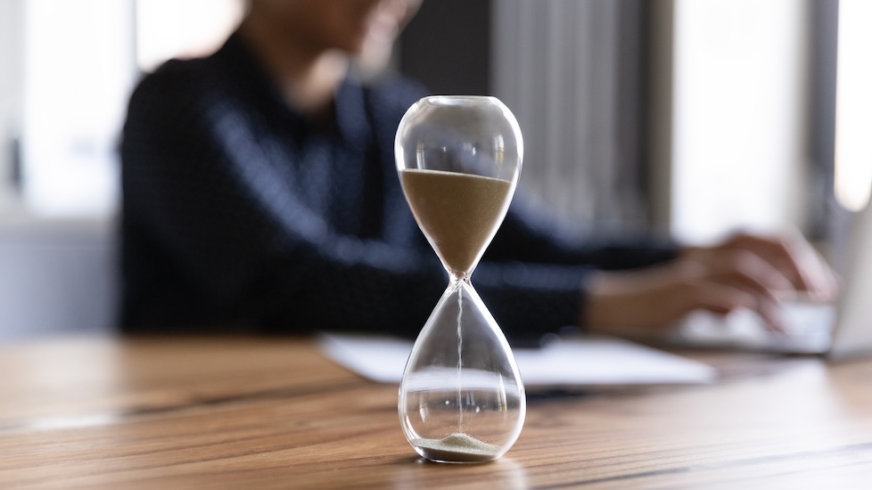 Hourglass with a postgraduate diploma student working on a laptop