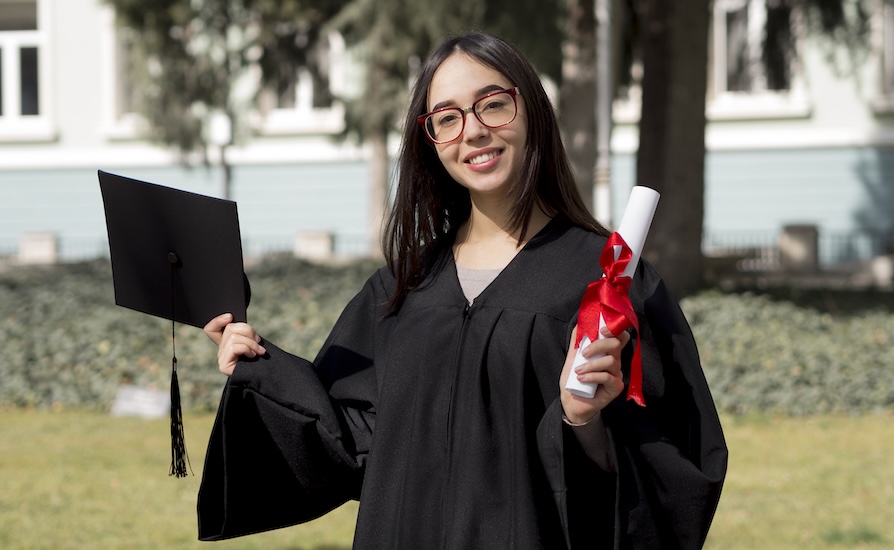 A girl at graduation, showing her degree with honours