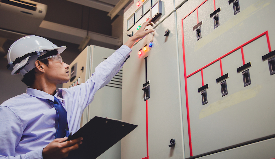 Electrical engineer checking voltage by voltmeter in control panel